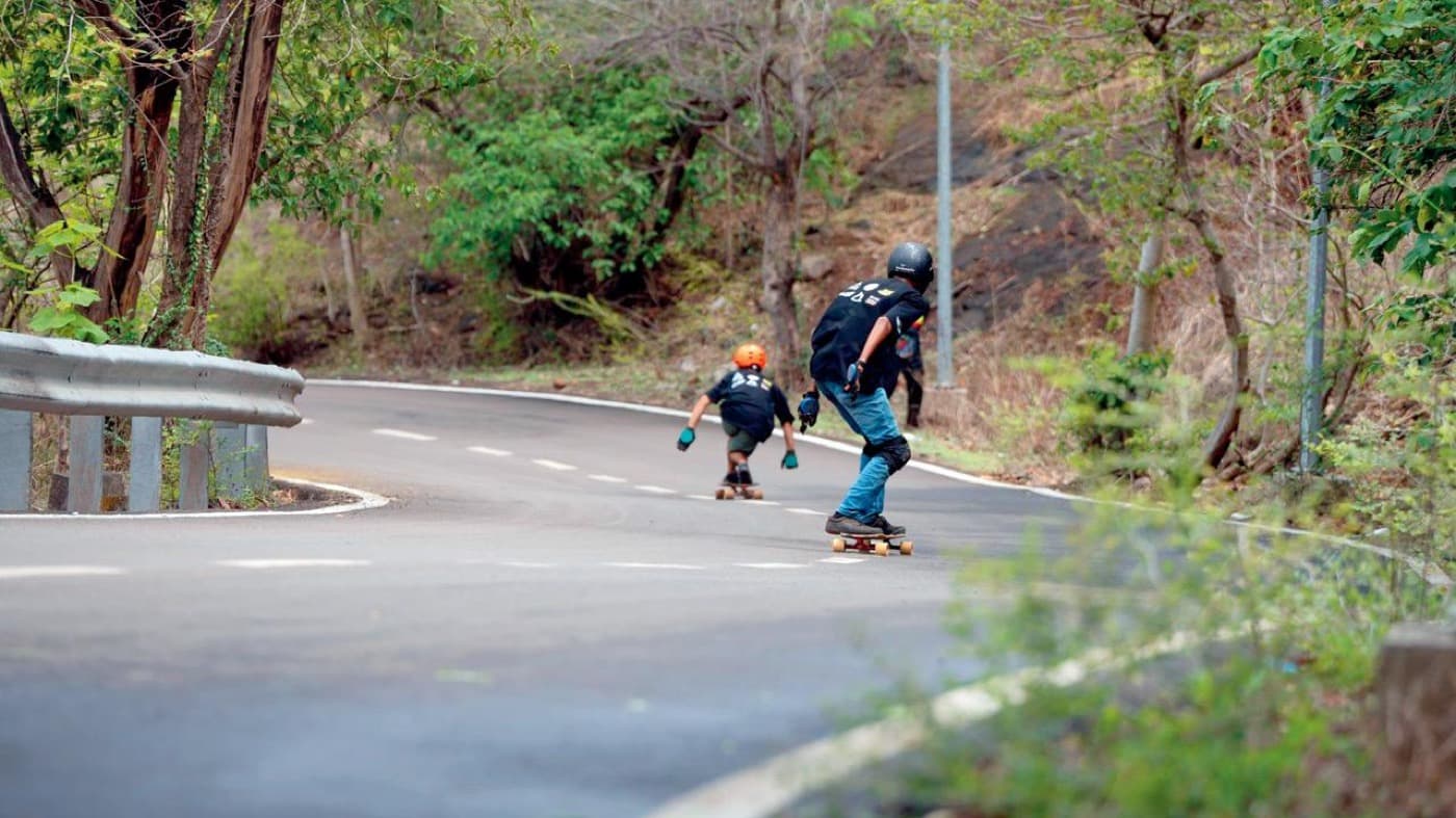 Protected downhill longboarders riding at Parsik Hill in India